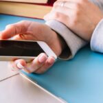 person-touching-mobile-phone-desk_23-2147978226