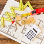 elevated-view-measure-tape-stacked-coins-key-calculator-blueprint_23-2147863919